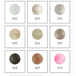 Op de afbeelding: Negen verschillende kleuren borduurgaren, elke kleur is opgerold tot een bol en wordt getoond in een vierkante doos met een nummerlabel. De kleuren zijn wit, cr&egrave;me, beige, lichtbruin, donkerbruin, groen en roze.