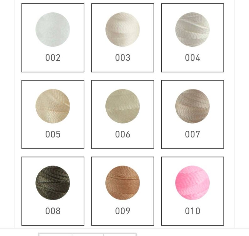 Op de afbeelding: Negen verschillende kleuren borduurgaren, elke kleur is opgerold tot een bol en wordt getoond in een vierkante doos met een nummerlabel. De kleuren zijn wit, cr&egrave;me, beige, lichtbruin, donkerbruin, groen en roze.