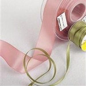 May include: Two spools of ribbon, one in a dusty rose color and the other in a muted olive green. Both ribbons are satin and have a subtle sheen.
