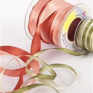 May include: A spool of three different colored satin ribbon. The ribbon is in shades of green, peach, and red. The ribbon is wound around a clear plastic spool with a yellow label.