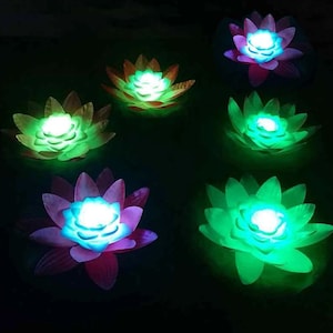 May include: Six floating lotus flower lights with different colored LED lights. The lights are in the shape of lotus flowers with multiple layers of petals. The lights are glowing in the dark.
