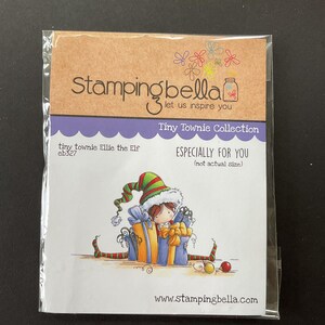 May include: A package featuring a Tiny Townie Ellie the Elf stamp from Stamping Bella. The illustration shows a cartoon elf with a green and red hat, surrounded by gifts. The text "ESPECIALLY FOR YOU" is also visible.