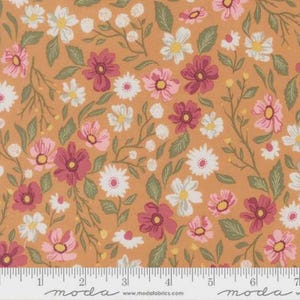 May include: A cotton fabric featuring a repeating floral pattern with pink, dark magenta, and white flowers on a warm orange background. A white ruler is visible at the bottom edge, showing measurements in inches up to 7 inches.