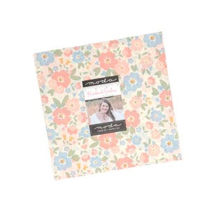 May include: A square stack of fabric squares featuring a floral pattern with light pink, blue, and yellow flowers on a cream background. A paper band across the center displays the text "moda", "Handmade Sweetness", and "moda FABRICS + SUPPLIES".