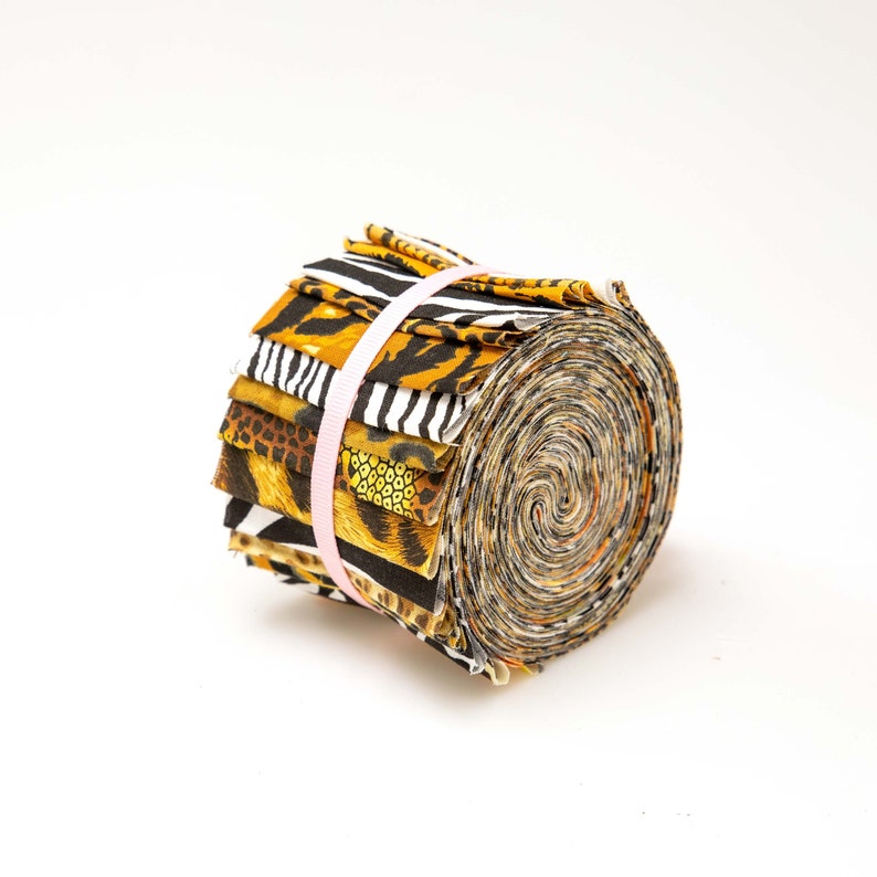 May include: A roll of fabric scraps featuring various animal print patterns in shades of brown, black, and white. The fabric is tied together with a pink ribbon.