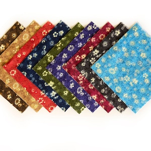 May include: A collection of ten fabric squares in various colors, each adorned with a floral pattern. Colors include brown, tan, red, navy, olive, purple, burgundy, black, and turquoise. The floral design features small white flowers with gold accents.