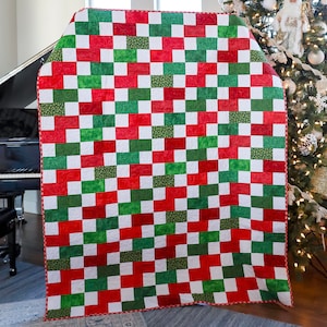 May include: A red and green checkered quilt with a white background. The quilt is made of squares of fabric sewn together in a checkerboard pattern.