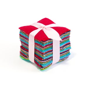 May include: A stack of colorful fabric squares tied together with a pink ribbon. The squares are in various shades of red, blue, green, and yellow.