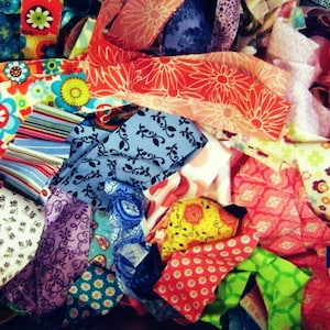 May include: A vibrant assortment of fabric scraps in various colors and patterns. The image showcases a mix of floral, striped, and geometric designs in shades of red, blue, green, and orange. Ideal for quilting or crafting projects.