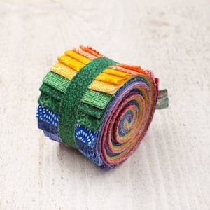 May include: A roll of colorful fabric scraps in a rainbow pattern, tied with a green ribbon. The fabric is folded and rolled into a spiral shape.