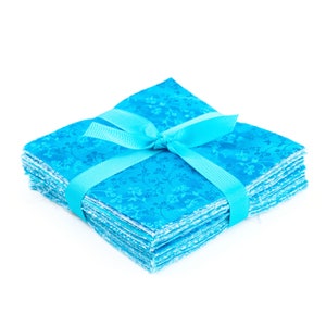 May include: A stack of square, turquoise fabric pieces tied with a matching ribbon. The fabric has a subtle floral pattern. The ribbon is tied in a bow, creating a neat and decorative package. The fabric squares are likely for quilting or crafting.