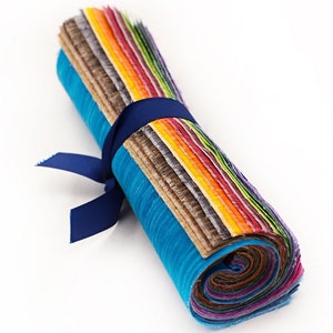 May include: A roll of colorful fabric scraps tied with a blue ribbon. The fabric is arranged in a rainbow pattern, with shades of brown, orange, yellow, green, blue, and purple.