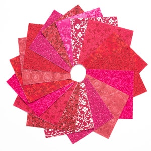 May include: A collection of 15 red and pink fabric squares with various floral and swirl patterns arranged in a circle.