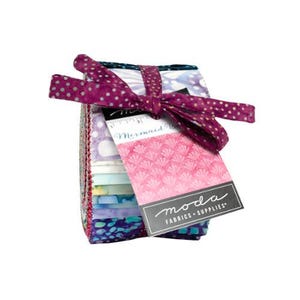 May include: A stack of fabric squares in various colors and patterns, tied with a purple polka dot ribbon. A tag with the words "Mermaid Cove" and "moda FABRICS + SUPPLIES" is attached to the fabric bundle.