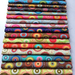 May include: A stack of colorful fabric featuring a repeating pattern of concentric circles in various shades of red, orange, yellow, green, blue, and purple. The fabric is arranged in a stack, with each layer slightly offset from the one below it.