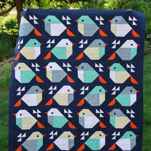 May include: A navy blue quilt featuring a repeating pattern of geometric birds. The birds are composed of white, teal, and yellow-green shapes with orange beaks and black eyes. White and gray geometric shapes are also present.