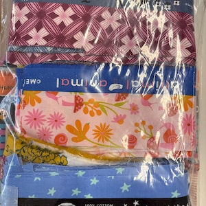 May include: A package of assorted fabric strips with various patterns. Designs include floral, geometric, and animal prints in pink, blue, and orange. The text "100% Cotton Made in Japan" and "gaze at the s" are visible.