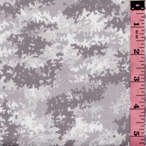May include: A fabric featuring a digital camouflage pattern in shades of white, light gray, and dark gray. A pink measuring tape is positioned along the right edge, showing markings in inches from 1 to 5 inches for scale and reference.