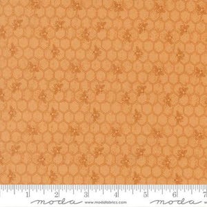 May include: A light orange fabric featuring a repeating pattern of dark orange hexagonal honeycomb shapes and small bees. A white measuring tape is visible at the bottom edge, showing a scale in inches from zero to seven inches.