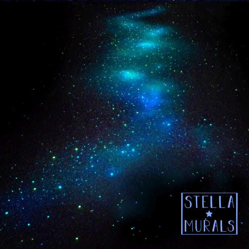 Pu&ograve; includere: Un'opera d'arte celeste che raffigura la Via Lattea su uno sfondo scuro. L'immagine mostra una scia luminosa di stelle blu e verdi, con il testo "STELLA MURALS" in un riquadro bianco in basso a destra.