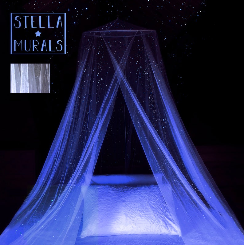 May include: A white canopy bed with a blue glow-in-the-dark star pattern. The canopy is made of a sheer fabric and is draped over a bed with a white pillow. The text "STELLA MURALS" is visible in the top left corner of the image.