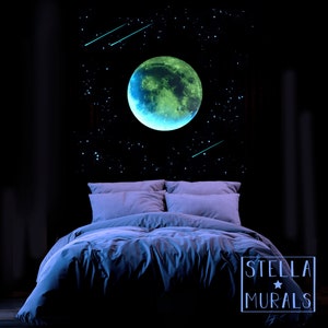 May include: A glowing wall mural featuring a large, green and blue moon, stars, and shooting stars above a bed with gray bedding. The mural is set against a dark background. The text "STELLA MURALS" is in the lower right corner.
