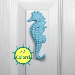 May include: A light blue seahorse-shaped hook mounted on a white door. The hook is secured with two screws. A circular graphic with the text "72 Colors!" is in the lower left corner.