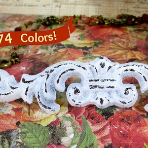 May include: White distressed decorative furniture pull with ornate scrollwork. The image includes the text "74 Colors!" on a red banner. The pull is set against a floral background.