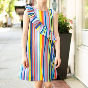 May include: A sleeveless dress with a colorful striped pattern and a single ruffle on the left shoulder. The dress is made of a lightweight fabric and has a casual, summery feel.