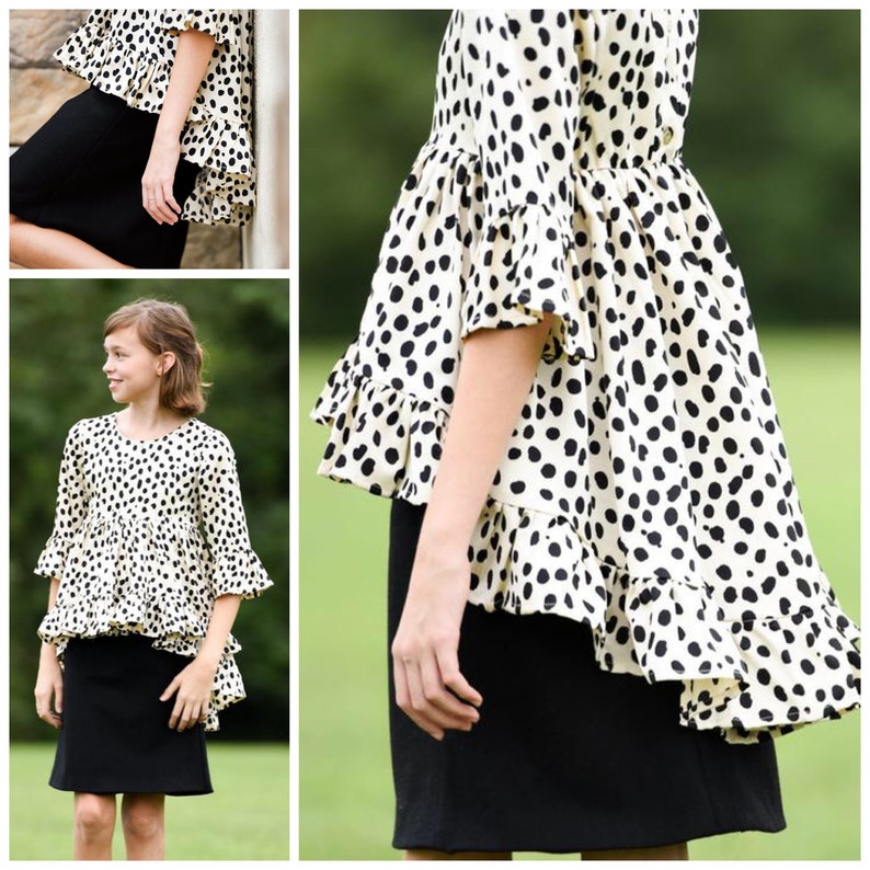 May include: A cream-colored top with a black dalmatian-style spot pattern, featuring three-quarter length sleeves with ruffled cuffs and a high-low hemline with a ruffled edge, paired with a solid black knee-length skirt.