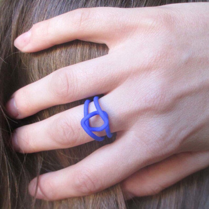 Puede incluir: Un anillo azul con un dise&ntilde;o geom&eacute;trico. El anillo est&aacute; hecho de un material liso y mate.