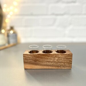 May include: A wooden tray with three clear glass vials. The tray is made of dark wood with a natural grain pattern.