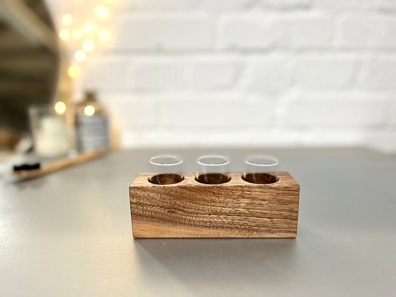 May include: A wooden tray with three clear glass vials. The tray is made of dark wood with a natural grain pattern.