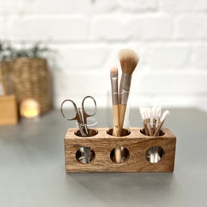 May include: Wooden organizer with four glass tubes for storing makeup brushes and cotton swabs. The organizer has a natural wood finish and is perfect for organizing your bathroom counter.