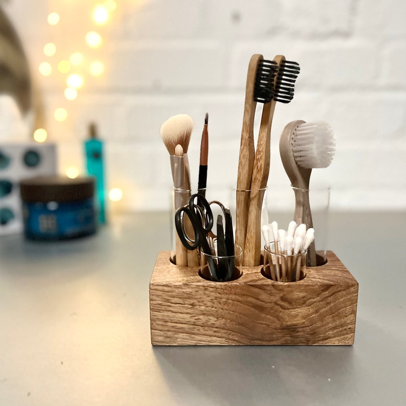 May include: Wooden organizer with six glass tubes, holding various items like toothbrushes, makeup brushes, and cotton swabs. The organizer is made of natural wood with a brown finish.
