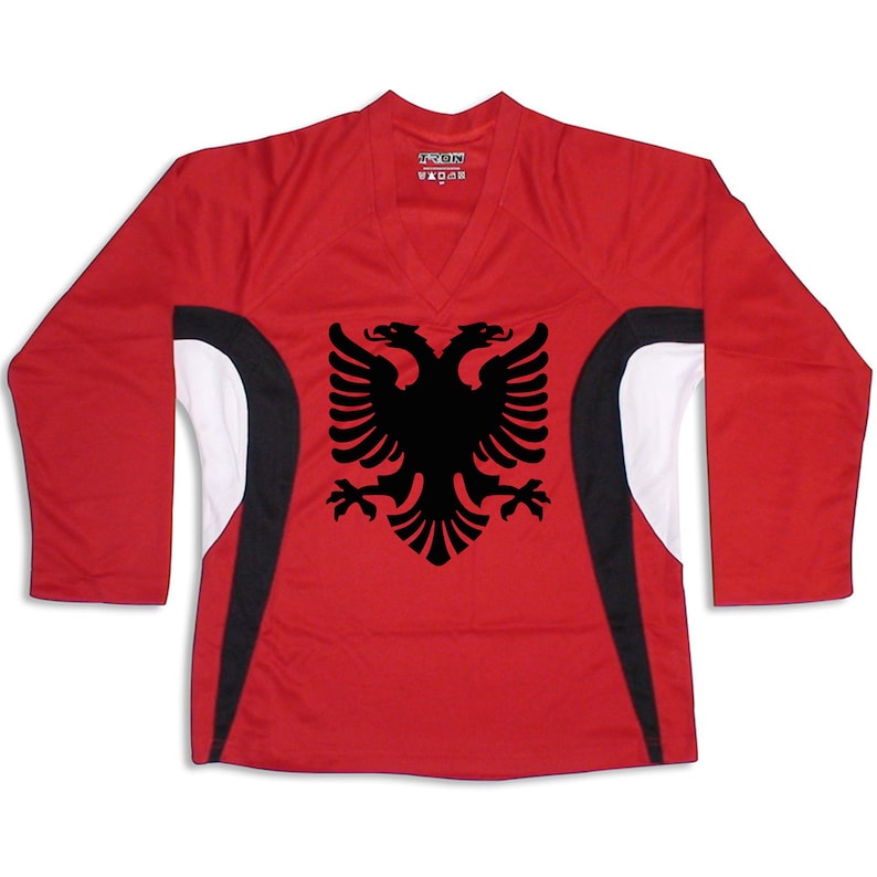 Puede incluir: Camiseta roja de manga larga con detalles en blanco y negro. La camiseta presenta un gr&aacute;fico de &aacute;guila bic&eacute;fala negra en la parte delantera.