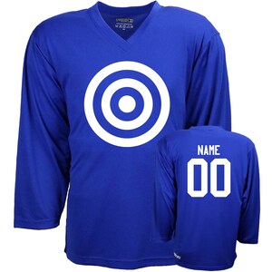 Puede incluir: Una camiseta de hockey azul real con un dise&ntilde;o de diana blanca en la parte delantera y el texto "NAME 00" en la parte posterior.