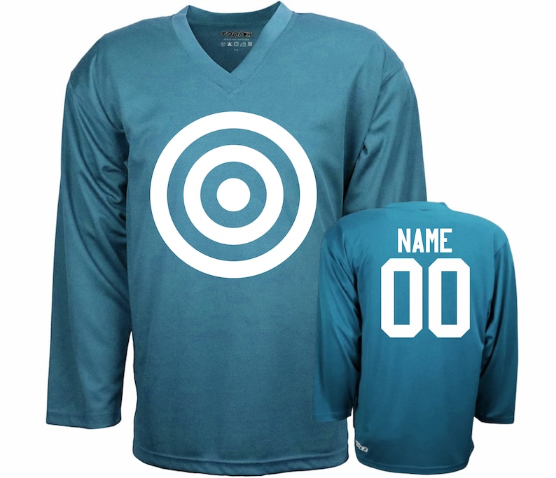 Puede incluir: Una camiseta de hockey azul turquesa con un dise&ntilde;o de diana blanca en la parte delantera y el texto "NAME 00" en la parte posterior.