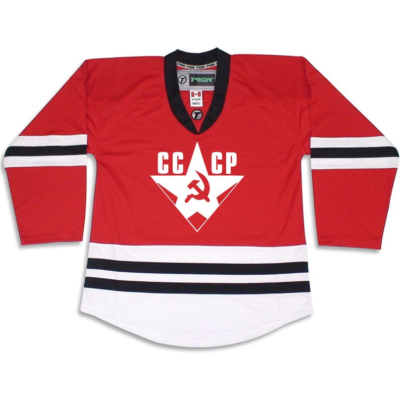 Puede incluir: Jersey de hockey rojo y blanco con rayas negras. El jersey tiene una gran estrella blanca con un martillo y una hoz dentro y el texto "CCCP" encima.