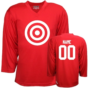 Puede incluir: Camiseta de hockey roja con un dise&ntilde;o de diana blanca en la parte delantera y el texto "NAME 00" en la parte posterior.
