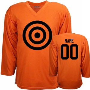 Puede incluir: Camiseta de hockey naranja con un dise&ntilde;o de diana negra en la parte delantera y el n&uacute;mero 00 y la palabra "NAME" en la parte trasera.