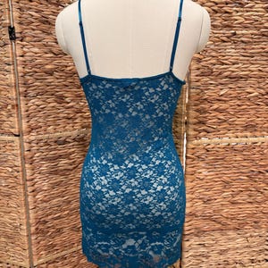K&ouml;nnte beinhalten: Ein tealfarbenes Spitzen-Slip-Kleid auf einer Schaufensterpuppe. Das Kleid hat zarte florale Spitzendetails und d&uuml;nne Spaghettitr&auml;ger. Das Kleid hat eine Mini-L&auml;nge.