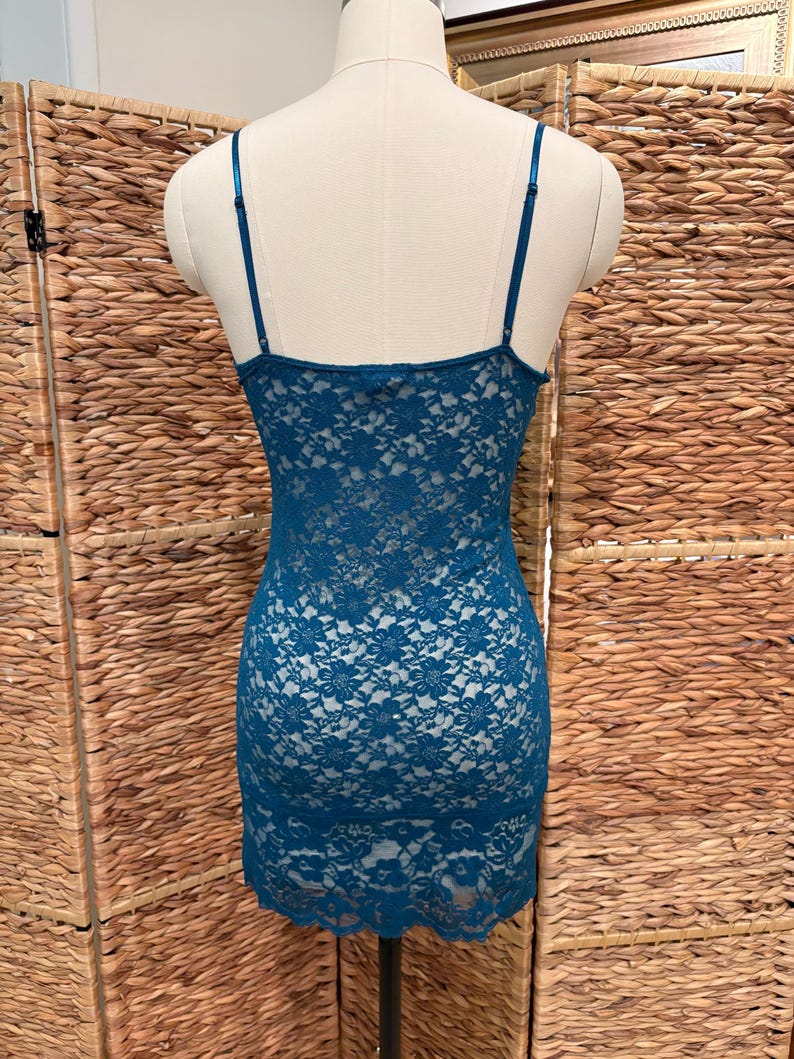 K&ouml;nnte beinhalten: Ein tealfarbenes Spitzen-Slip-Kleid auf einer Schaufensterpuppe. Das Kleid hat zarte florale Spitzendetails und d&uuml;nne Spaghettitr&auml;ger. Das Kleid hat eine Mini-L&auml;nge.