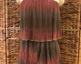 May include: A strapless, two-piece outfit on a mannequin. The top and shorts are made of pleated fabric with a color gradient from pink to gray. The outfit has a shimmering, metallic appearance, suggesting a party or special occasion garment.