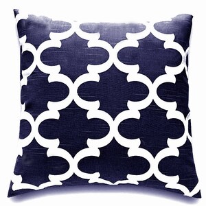 K&ouml;nnte beinhalten: Ein marineblaues Kissen mit einem wei&szlig;en geometrischen Muster. Das Muster ist ein sich wiederholendes Design aus ineinandergreifenden Kreisen und B&ouml;gen.