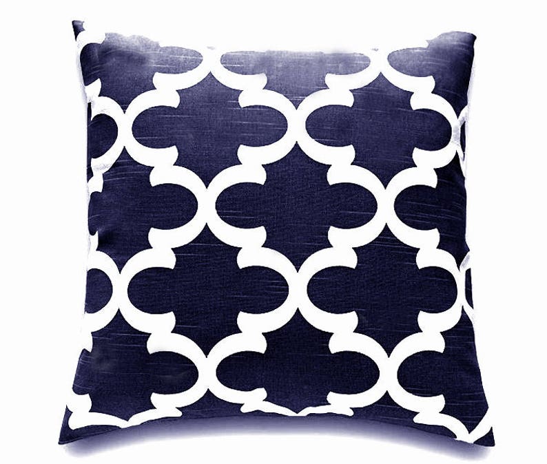 K&ouml;nnte beinhalten: Ein marineblaues Kissen mit einem wei&szlig;en geometrischen Muster. Das Muster ist ein sich wiederholendes Design aus ineinandergreifenden Kreisen und B&ouml;gen.