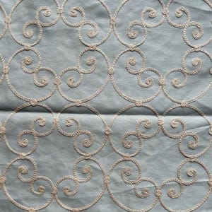 May include: A light blue fabric with a white embroidered pattern of swirling circles.