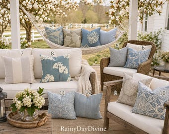 May include: A collection of twelve square throw pillows in various blue, white, and beige patterns, including floral, striped, and geometric designs, displayed on outdoor furniture with the text RainyDayDivine at the bottom.