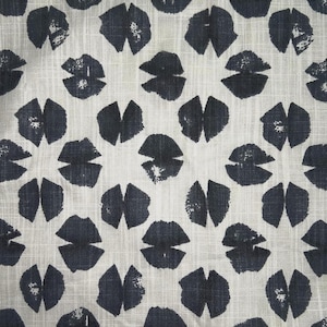 Puede incluir: Una tela con un patrón repetido de formas abstractas azul marino oscuro, que se asemejan a labios o pétalos. Las formas están dispersas sobre un fondo beige claro con una sutil textura tejida.