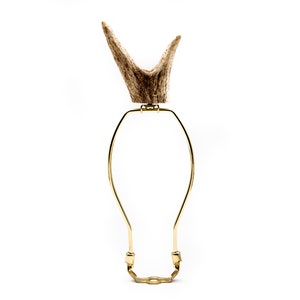 May include: A gold lamp harp with a natural antler finial. The harp is made of metal and has a simple design.
